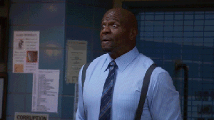 The cast of Brooklyn 99 cheers with arms up in the arm and big smiles.