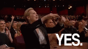 Meryl Streep stands in an audience at an award show and points to the stage; the caption reads YES.