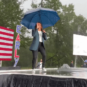 gif of Kamala Harris dancing in the rain on a stage, holding an umbrella